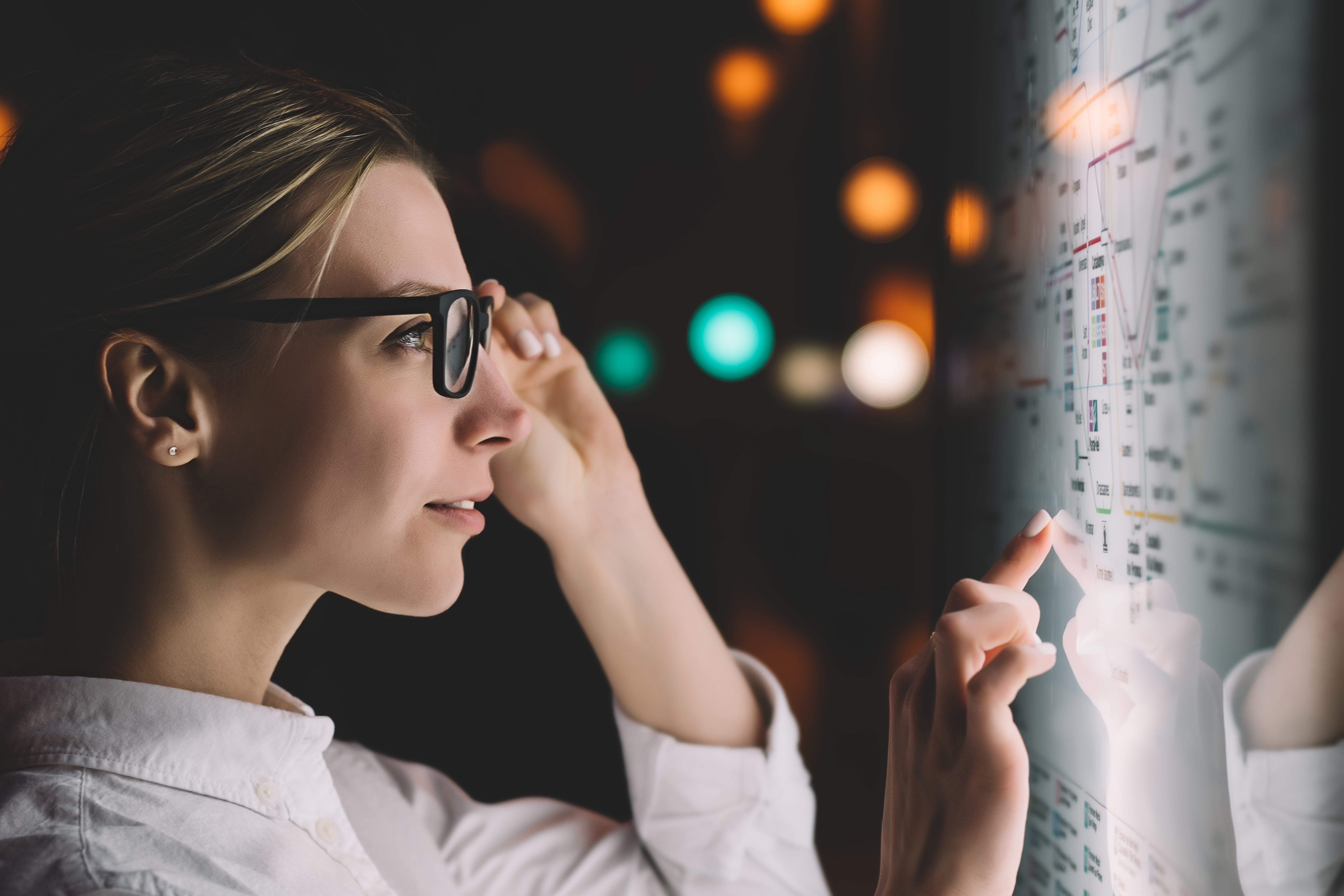 A woman wearing glasses while looking at a whiteboard.