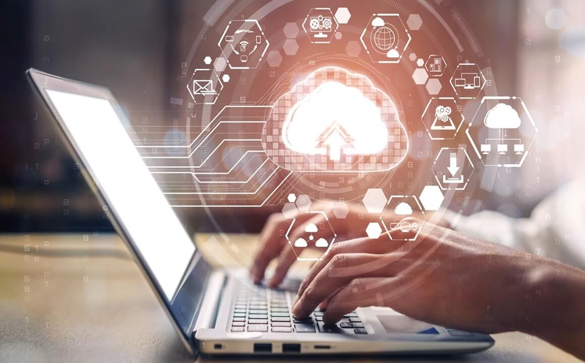 Hands typing over laptop with a cloud graphic