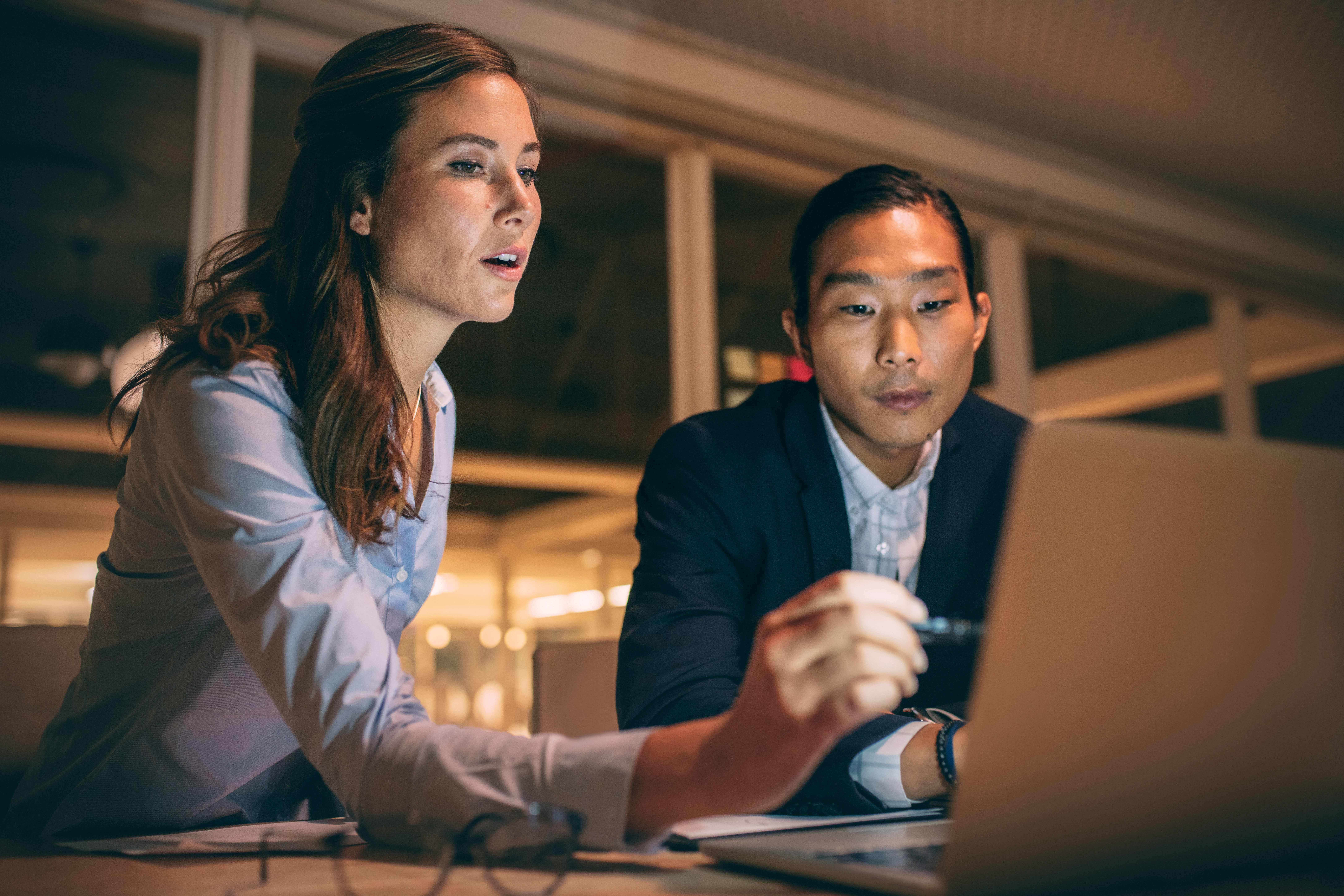 Male and female coworkers collaborating over a laptop in the office