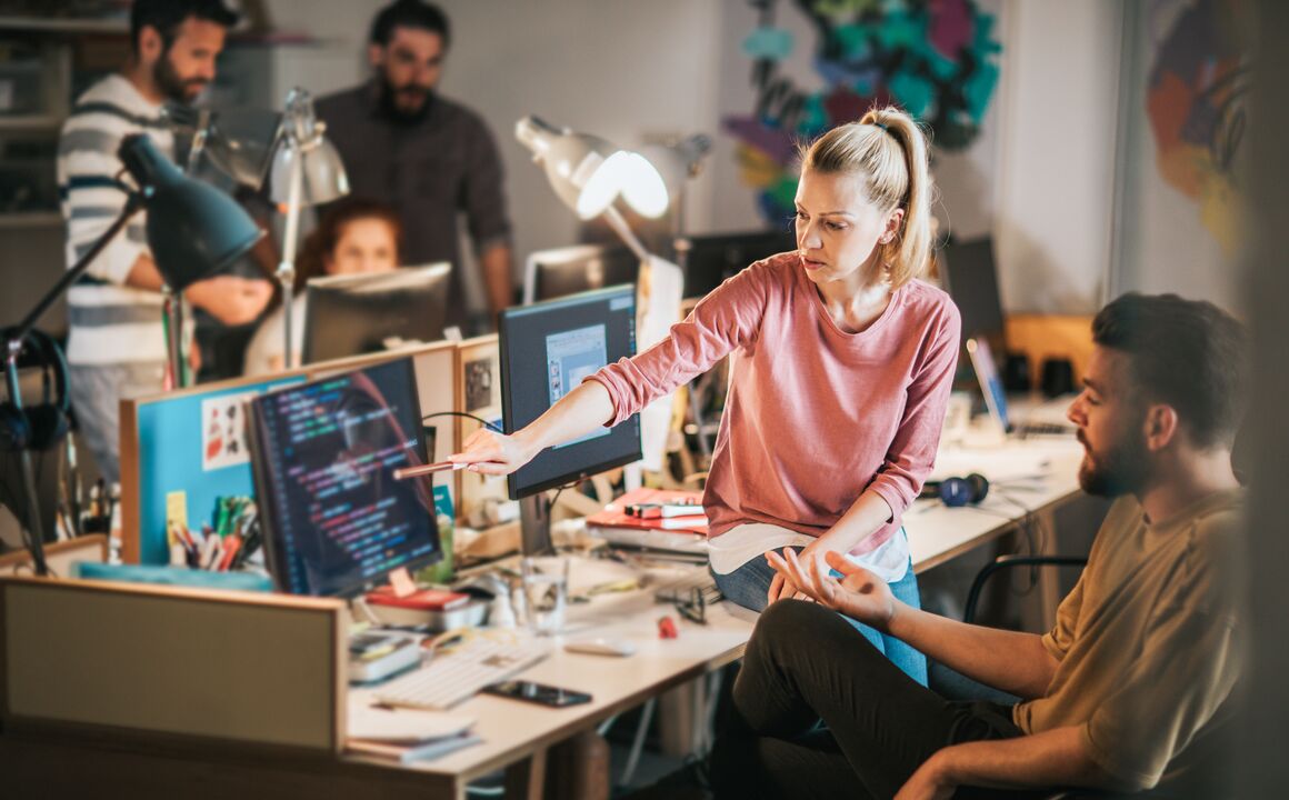 Woman pointing at man's monitor.