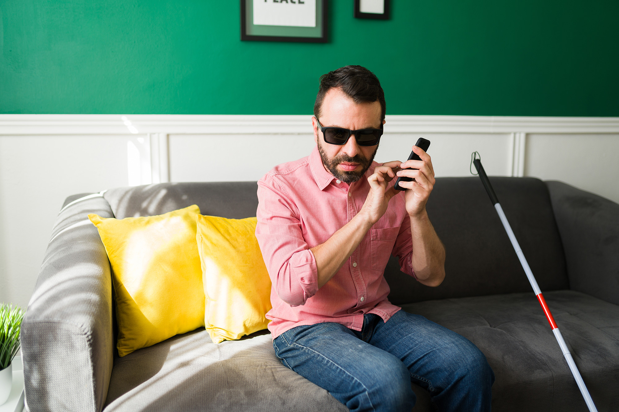 Blind man sitting on couch using phone to access a digitally accessible website