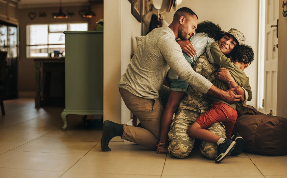 Family hugging their military mother