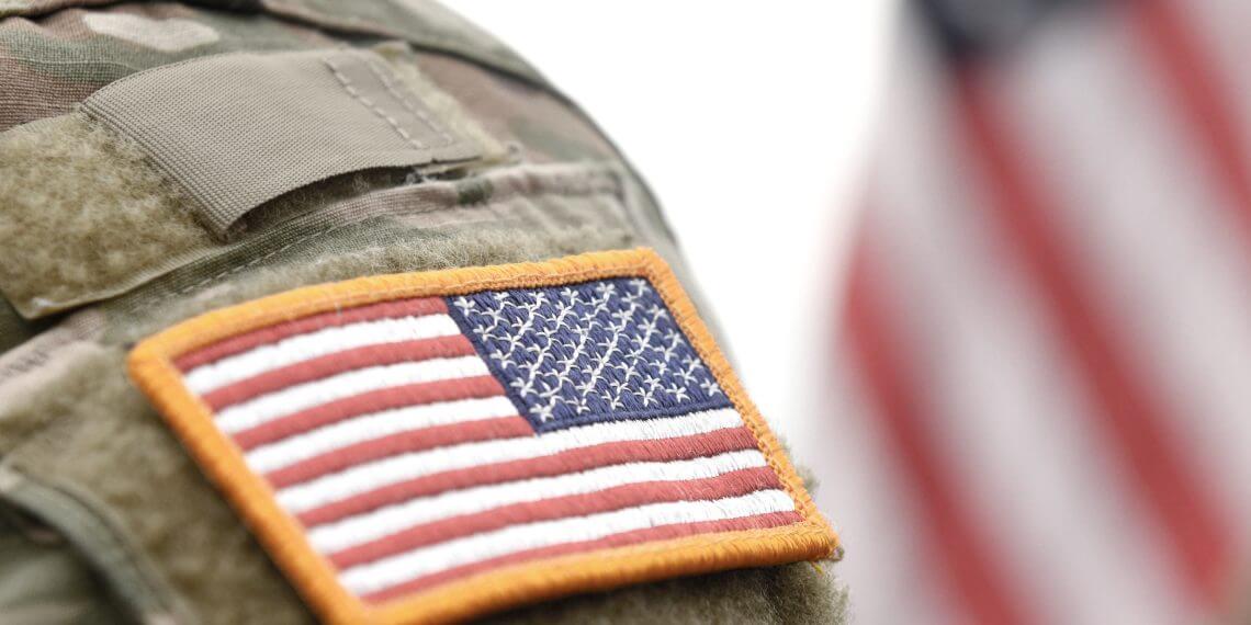 Service member's arm, showcasing American flag badge 