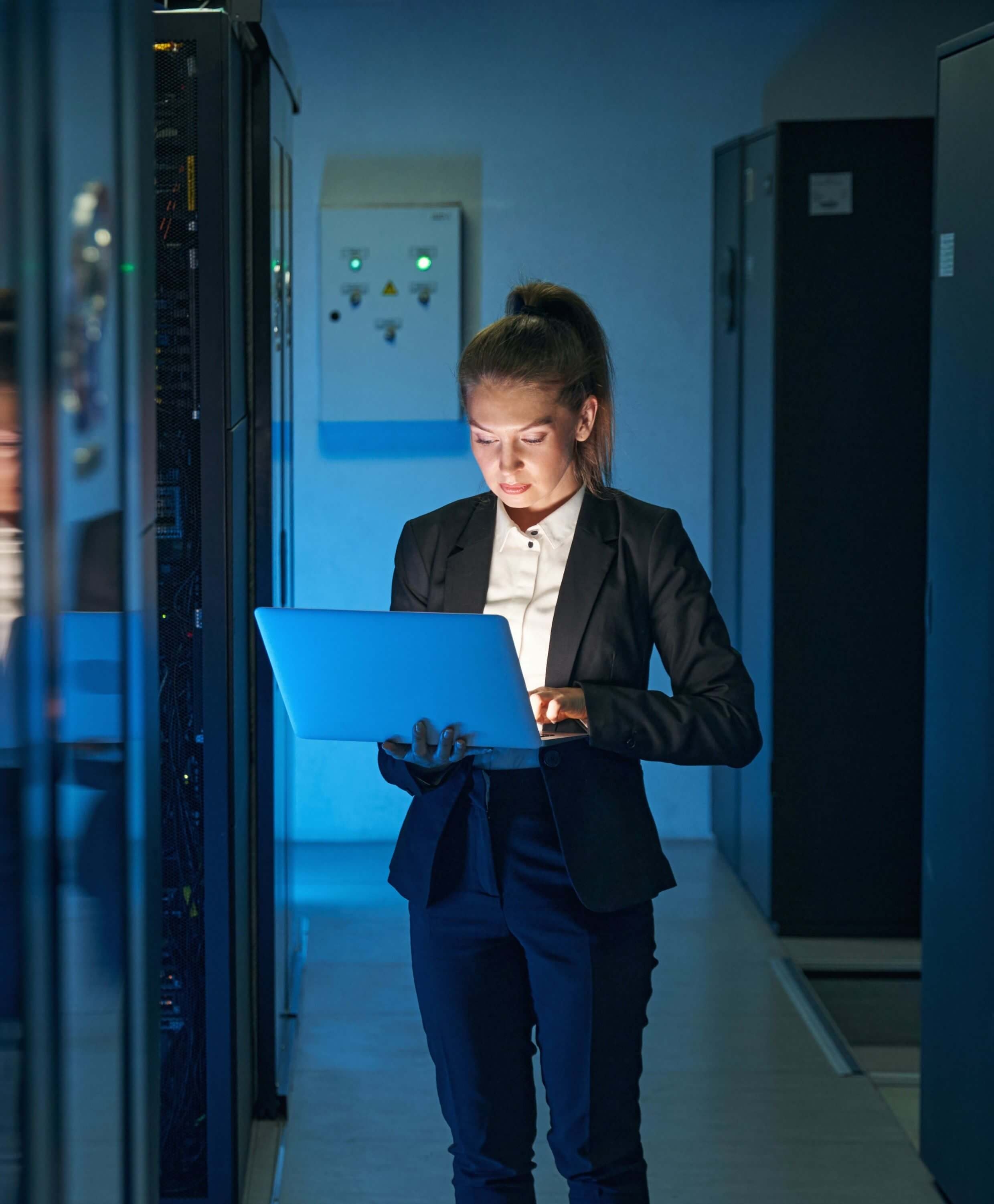 professional woman holding laptop in server room